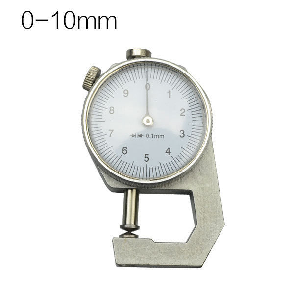 A dial thickness gauge with a silver body and dial, placed on a grey surface, with a yellow box in the background having Chinese characters printed on it.