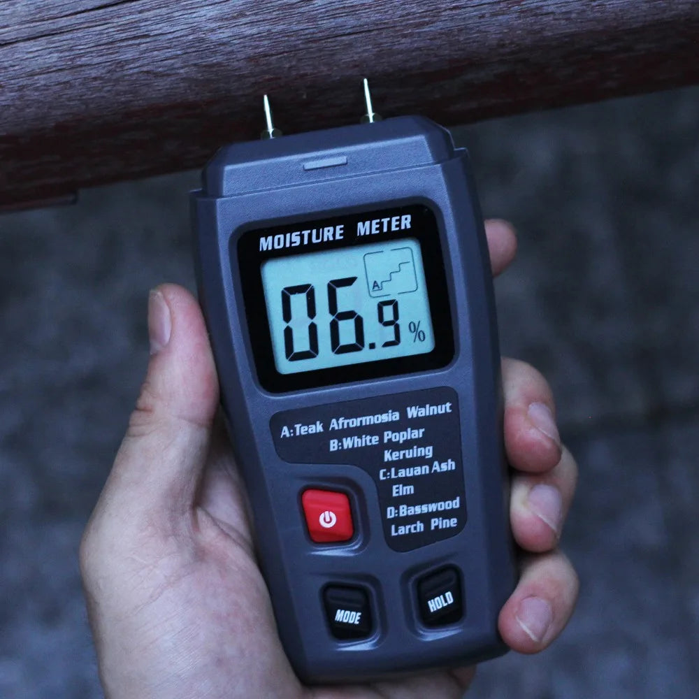 Digital moisture meter being held over a wooden surface