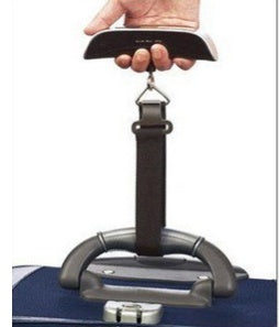 A hand holding a black luggage scale with a green LCD screen displaying weight, featuring a hook and button for operation.