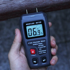 Digital moisture meter being held over a wooden surface