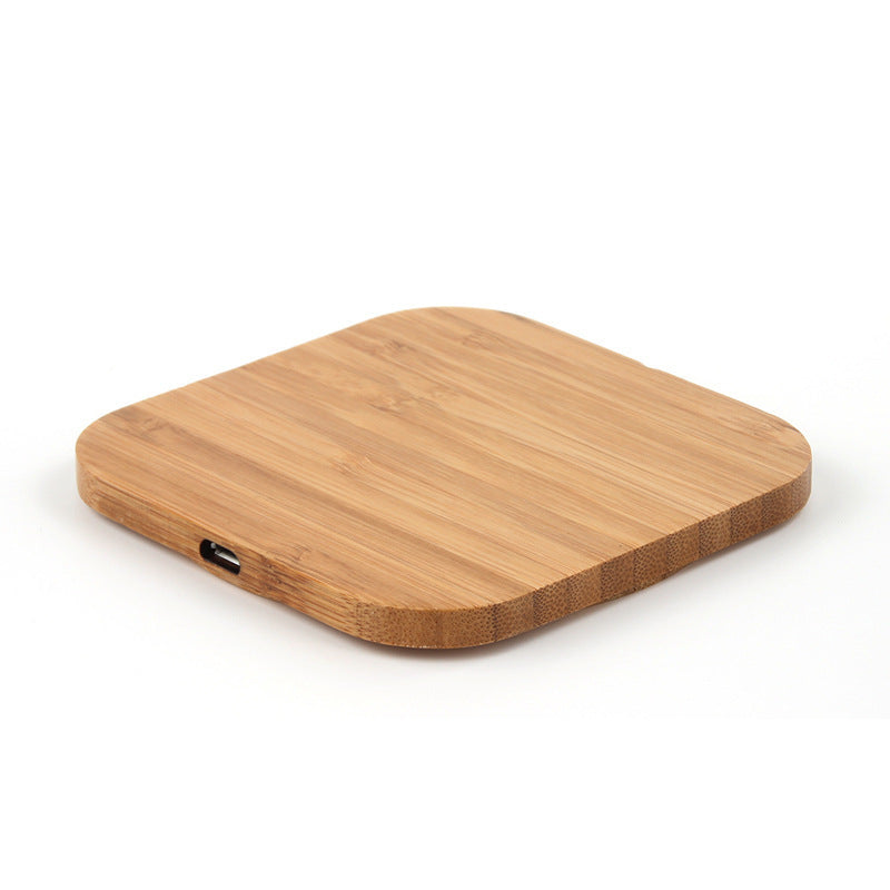 A wooden bamboo wireless charger with a USB port, in a square shape.