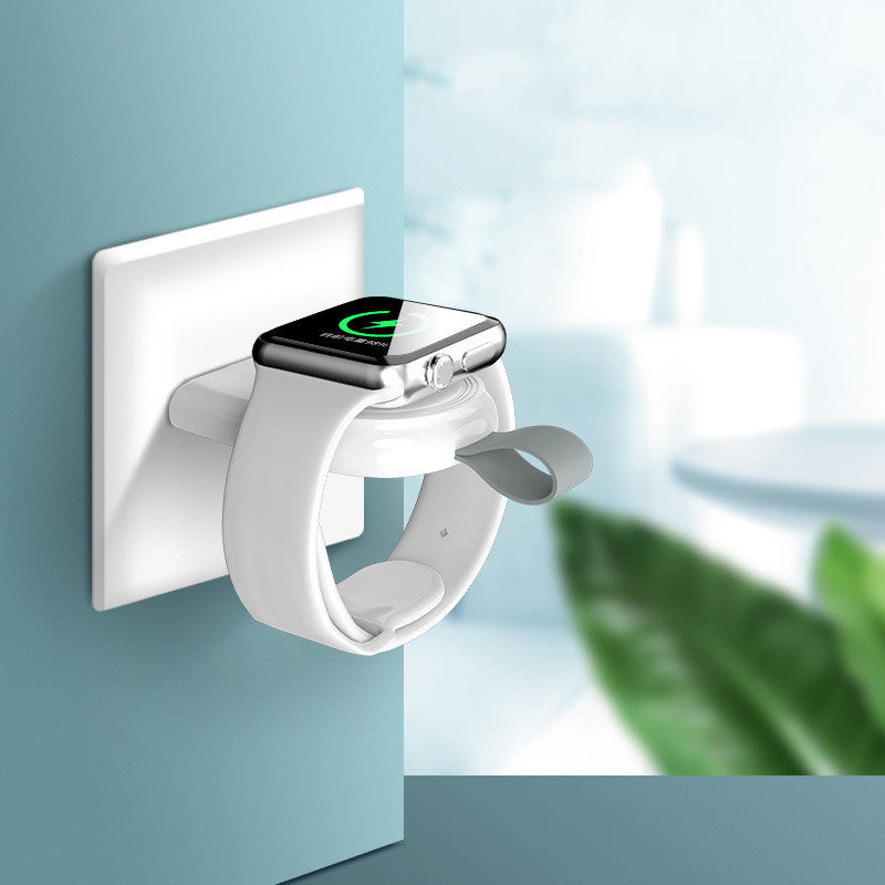 A white wireless charger mounted on a wall, charging a white Apple Watch.