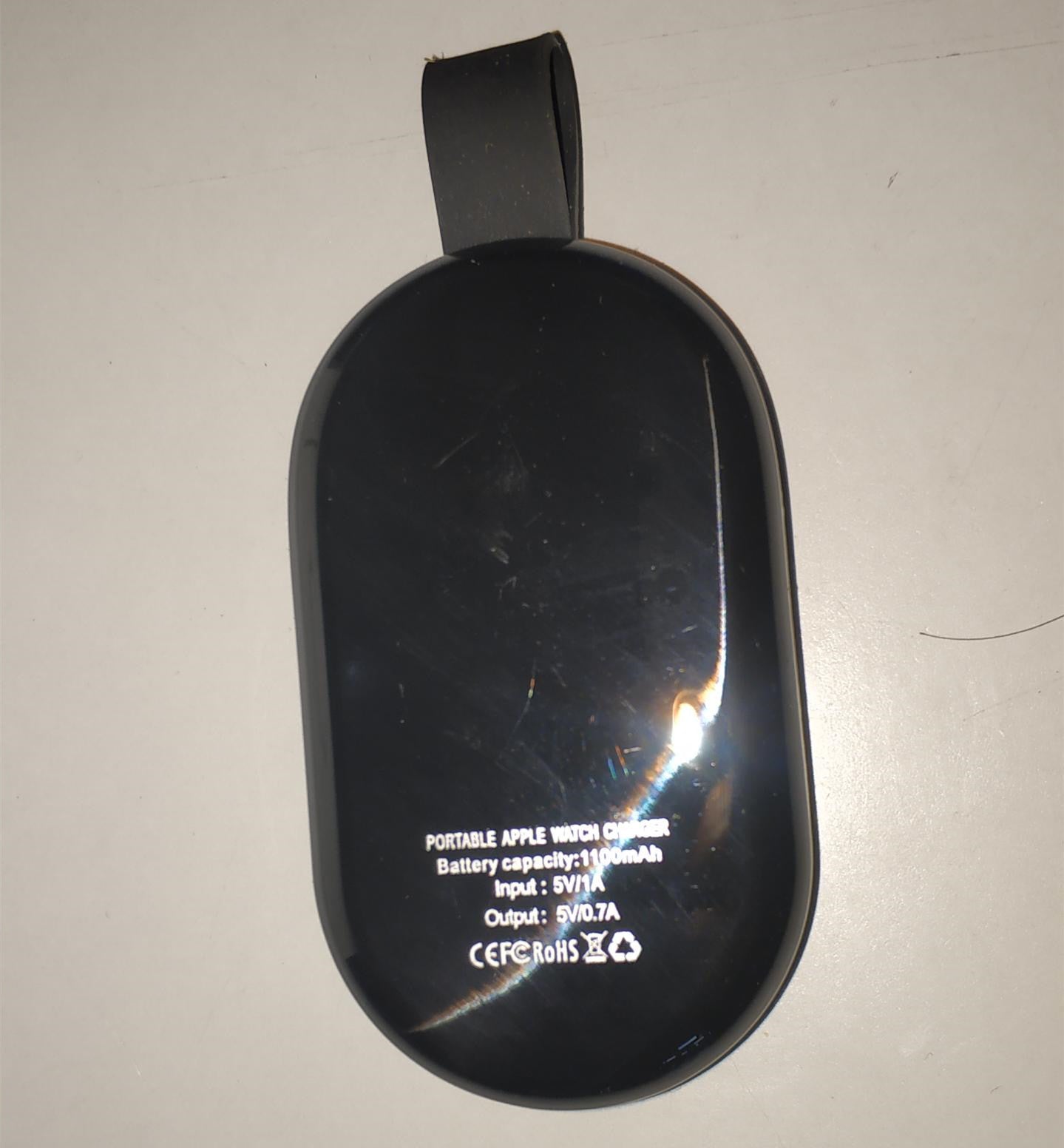 A white wireless charger mounted on a wall, charging a white Apple Watch.