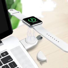 A white wireless charger mounted on a wall, charging a white Apple Watch.