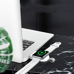 A white wireless charger mounted on a wall, charging a white Apple Watch.